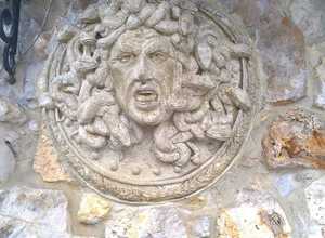 голова Медузы Горгоны на каменной стене дома